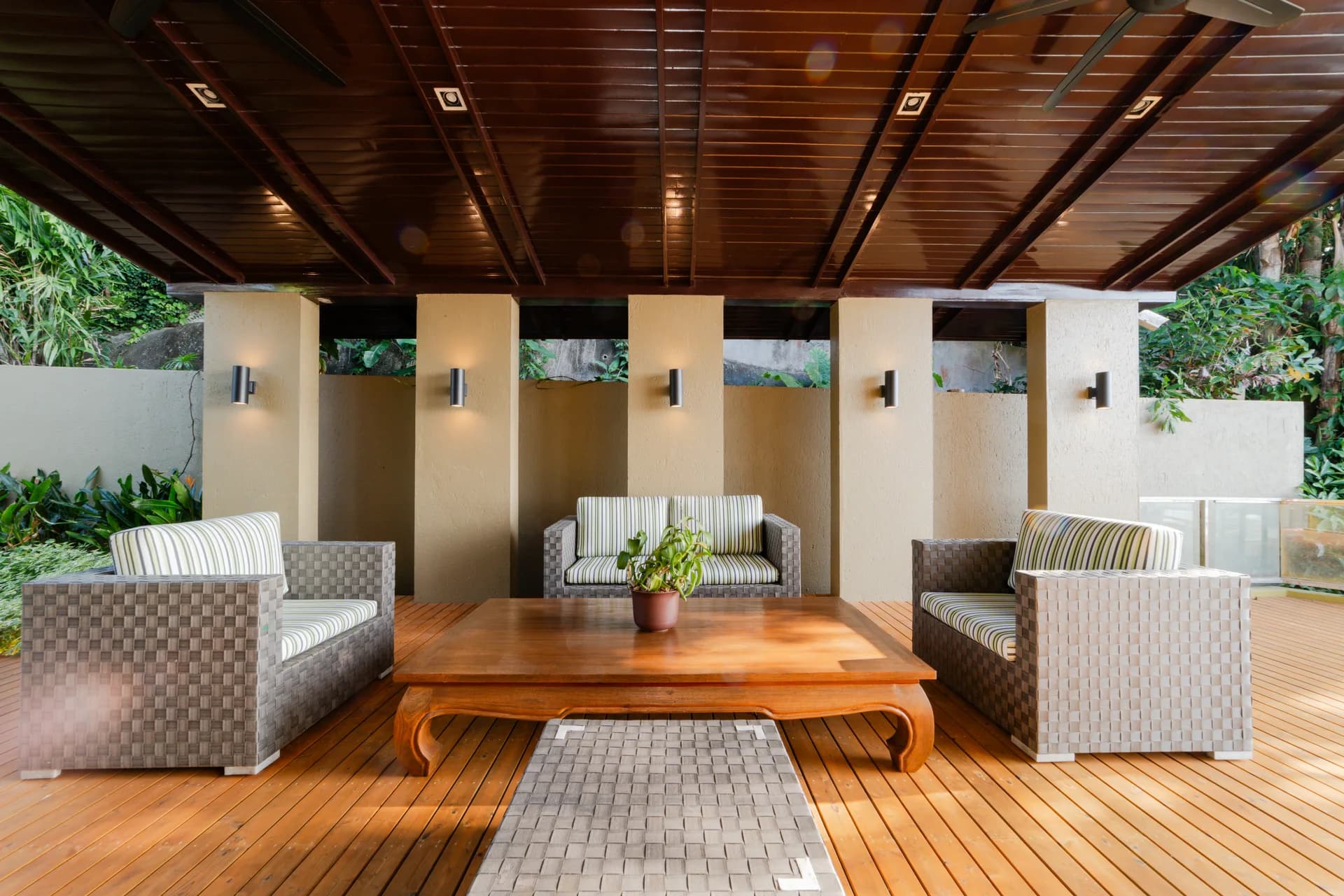A shaded timber terrace surrounded by tropical greenery at Villa 18